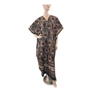 May include: A long, flowing caftan dress with a V-neck and short sleeves. The dress features a dark background with a repeating floral pattern in shades of brown and tan. The hemline has a decorative border.