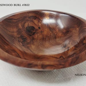 Op de afbeelding: Een gepolijste houten kom gemaakt van Karbor rozenhoutwortel, met een diepbruine kleur met wervelende nerfpatronen en donkere knoesten. De tekst KARBOR ROSEWOOD BURL #7832 en NELSONWOOD.NET is zichtbaar op het oppervlak van de afbeelding.
