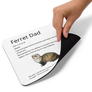Pode incluir: Um tapete de rato branco com uma borda preta. O tapete de rato apresenta uma definição de "Ferret Dad" com uma ilustração de furão. A definição diz: "[fair-it d-aa-d] substantivo Um pai orgulhoso cujos bolsos e coração estão sempre cheios de furões! Reconhecido por sua capacidade de transformar qualquer objeto doméstico em um brinquedo para furões ou um esconderijo aconchegante. Veja também: coordenador de dooking diário, pá, domador de furões."