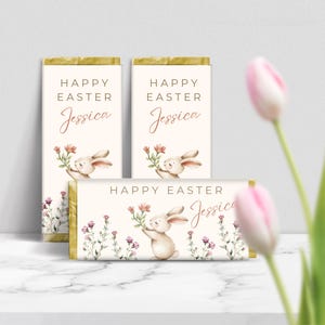 Könnte beinhalten: Drei personalisierte Schokoladentafel-Verpackungen mit einer Aquarell-Illustration eines Hasen, der Blumen hält. Die Verpackungen zeigen den Text "Frohe Ostern Jessica".
