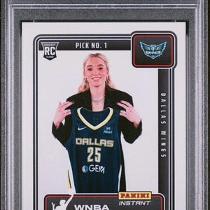 May include: A 2025 Panini Instant WNBA trading card featuring Paige Bueckers. The card displays Bueckers holding a Dallas Wings jersey. The card is graded GEM MT 10 by PSA and includes the text "Draft Night".
