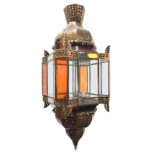 May include: A brass lantern with a geometric design and stained glass panels in shades of orange, yellow, green, and red. The lantern has a pointed top and a square base.