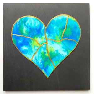 May include: A blue and green heart with gold cracks on a black background. The heart is painted in a watercolor style.
