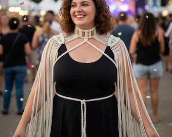 Peut inclure: Une pièce d'épaule en macramé couleur crème dotée d'un col montant avec des accents métalliques dorés verticaux. Le vêtement comprend de longues franges fluides qui tombent sur les épaules et une ceinture tressée avec des embouts dorés.