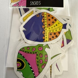 May include: A clear plastic bag containing several colorful fish stickers. The stickers feature various designs with bright colors like blue, orange, green, and pink. The bag has a black label that reads "Funky Fish Stickers".