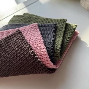 Puede incluir: Una pila de seis pa&ntilde;os cuadrados de punto en tonos marr&oacute;n, rosa, gris y verde. Los pa&ntilde;os est&aacute;n dispuestos en forma de abanico, con los bordes de cada pa&ntilde;o visibles. La textura del punto es claramente visible.