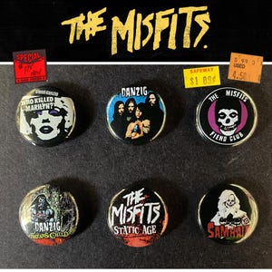 以下が含まれることがあります： ザ・ミスフィッツのバンドボタン6個セット。ボタンには、バンドのロゴ、スカルのイメージ、"Danzig"や"Static Age"などのテキストなど、さまざまなデザインが施されています。一部のボタンには値札が付いています。