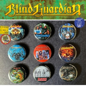 Könnte beinhalten: Eine Sammlung von neun runden Metallknöpfen mit Kunstwerken und dem Bandnamen "Blind Guardian". Die Knöpfe zeigen verschiedene Albumcover, Bandfotos und das Logo der Band. Der Hintergrund ist dunkel.