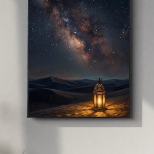 Puede incluir: Una impresión en lienzo enmarcada representa un paisaje desértico bajo un cielo estrellado. Una linterna brillante y ornamentada se encuentra sobre una duna de arena, proyectando una luz cálida. La obra de arte presenta azules oscuros, marrones y tonos dorados.