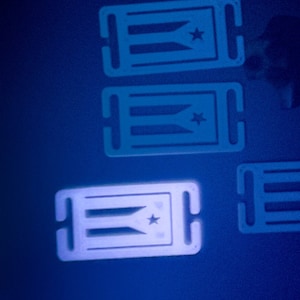 May include: Four white plastic keychains with a design of the Puerto Rican flag. The flag is white with three red horizontal stripes and a blue star in the upper right corner.
