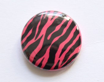 Puede incluir: Un botón redondo con estampado de cebra rosa y negro.