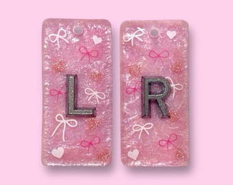 Rosa schimmernde anatomische Röntgenmarker mit Bögen und Glitzerherzen, personalisiert mit Initialen.
