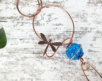 May include: Copper wire dragonfly garden decor with a blue glass orb. The dragonfly is attached to the wire and the orb hangs from the bottom.
