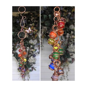 May include: A rainbow-colored glass bead wind chime with copper wire and a butterfly charm. The beads are arranged in a cascading pattern, with the colors of the rainbow.