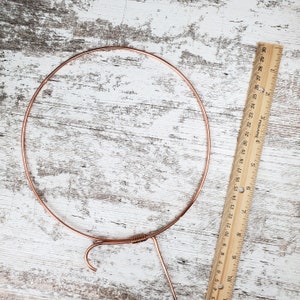 May include: A copper wire hoop with a hook on the bottom. The hoop is about 10 inches in diameter.