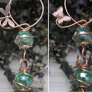 May include: A copper wire wind chime with two green iridescent glass balls and a dragonfly and butterfly charm.