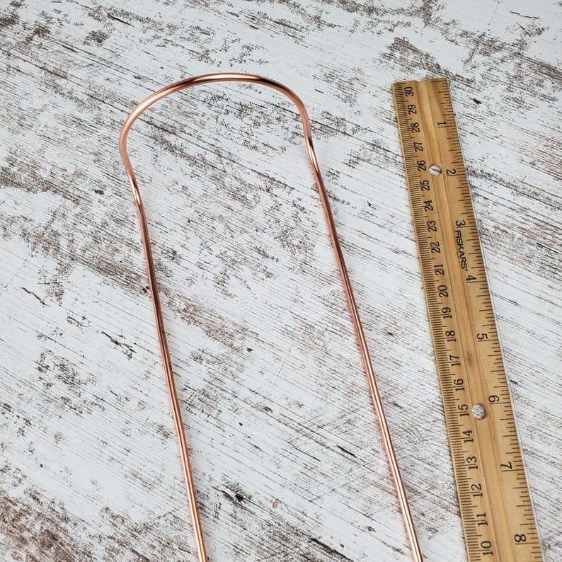 May include: A copper-colored metal hanger with a rounded top and two straight legs. The hanger is approximately 8 inches long.