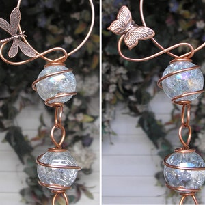 May include: Copper wire wind chime with two clear glass orbs wrapped in copper wire and a dragonfly and butterfly design.