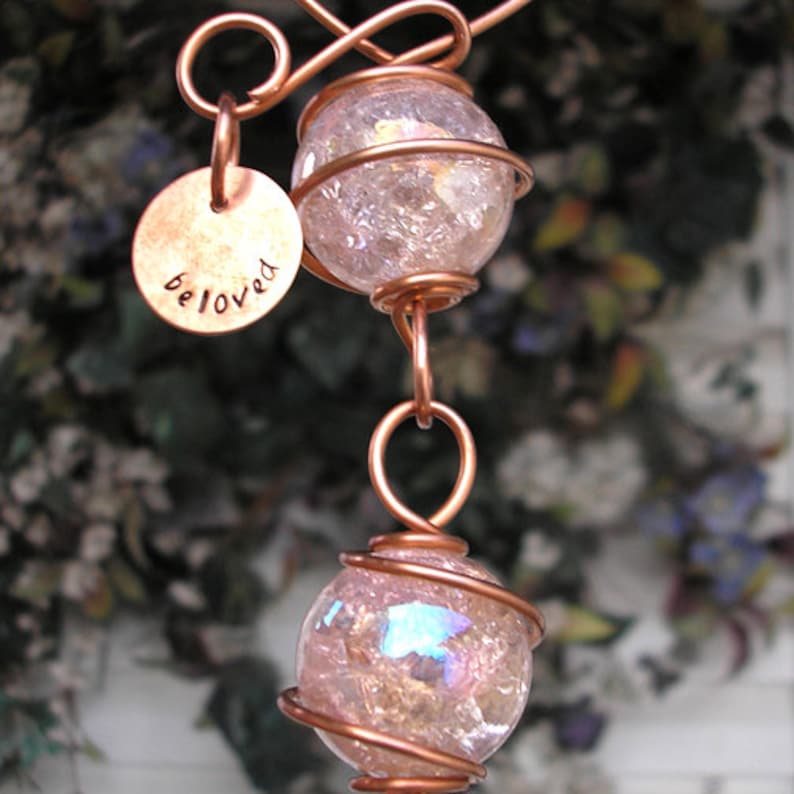 May include: A copper wire wrapped pendant with two iridescent glass orbs and a copper tag that says "beloved".