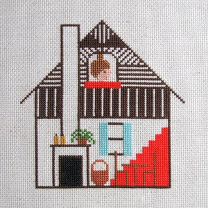 Puede incluir: Un patrón de punto de cruz de una casa con un techo rojo, una chimenea marrón, una ventana azul y una puerta marrón. La casa tiene un interior blanco con una chimenea, una planta y una escalera.