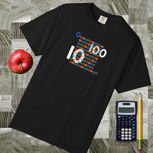 Puede incluir: Una camiseta negra de manga corta con un diseño gráfico compuesto por pequeños círculos multicolores que forman el texto "Goooooooo 10 100 go!". La prenda tiene cuello redondo y una etiqueta en el interior del cuello.