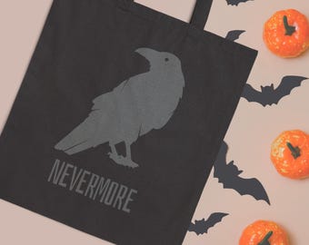 Może przedstawiać: Czarna torba z szarą ilustracją kruka i napisem "NEVERMORE". Obraz zawiera pomarańczowe dynie i czarne sylwetki nietoperzy, tworząc motyw Halloween.