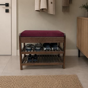 May include: A dark brown wooden shoe bench featuring a deep burgundy upholstered seat cushion. The bench includes two slatted storage shelves underneath, currently holding several pairs of casual footwear, including sneakers and sandals.