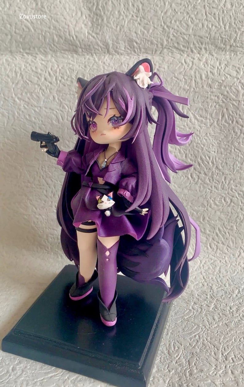 May include: Purple anime figurine with cat ears, holding a gun and wearing a purple dress and boots. The figurine is standing on a black base.