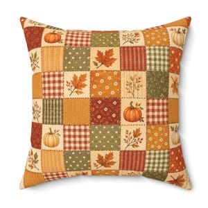 May include: A square throw pillow featuring a patchwork design of various autumn-themed patterns. The fabric squares display orange pumpkins, red maple leaves, green and white polka dots, red and white gingham, and floral motifs in warm tones.
