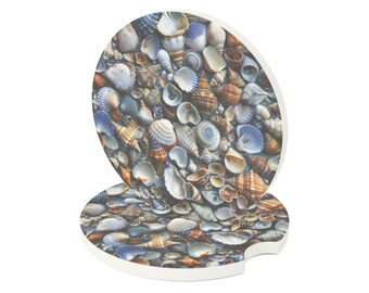 Può includere: Due sottobicchieri rotondi per auto con un design dettagliato di conchiglie. I sottobicchieri presentano una varietà di conchiglie nelle tonalità del bianco, marrone, blu e beige, creando una scena di spiaggia realistica. I sottobicchieri hanno un bordo bianco.