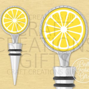 May include: Two bottle stoppers with a lemon slice design. The round top features a yellow lemon slice with white segments and a silver-colored rim. The stopper has a silver-colored stem and a black rubber base. The background is a light yellow color.