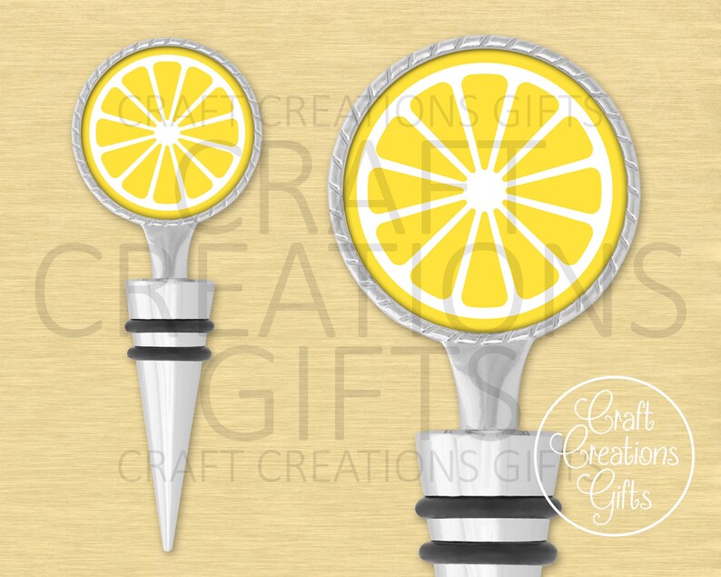 May include: Two bottle stoppers with a lemon slice design. The round top features a yellow lemon slice with white segments and a silver-colored rim. The stopper has a silver-colored stem and a black rubber base. The background is a light yellow color.
