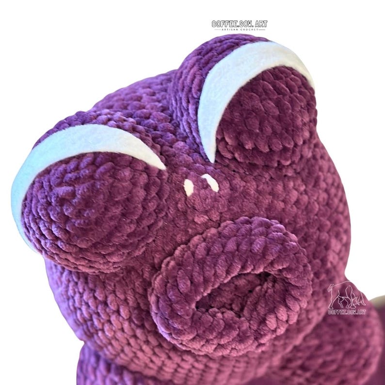 May include: Close-up of a plush, purple frog with large, round eyes and a wide mouth. The frog has white accents above the eyes. The image includes the text "GOFFES.COM.ART" in the upper right corner.
