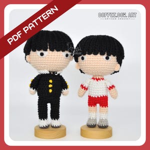 May include: Two crocheted amigurumi figures of boys, one in a black school uniform and the other in a red and white sports uniform. Both figures have black hair and are standing on wooden bases. The image includes the text "COFFEE.COW.ART - ARTISAN CROCHET -" and "PDF PATTERN".