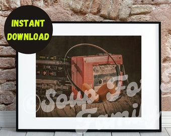 May include: A vintage cassette tape player with headphones resting on top. The player is red and has a cassette tape inserted. The headphones are black and have a brown cord. The player and headphones are sitting on a wooden surface.