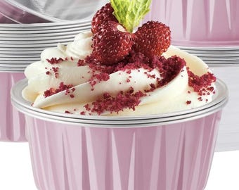 May include: A pink cupcake with white frosting, fresh strawberries, and red sprinkles. The cupcake sits in a fluted pink baking cup. Other cupcakes and clear lids are visible in the background. The cupcakes are for baking.