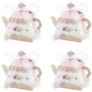 May include: Four pink teapot-shaped gift boxes with white floral designs and gold trim. Each box is topped with a white ribbon and has a handle and spout. The boxes are arranged in a square.