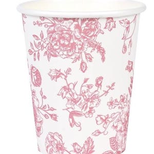 Op de afbeelding: Witte papieren beker met een roze bloemenpatroon. Het ontwerp toont gedetailleerde illustraties van rozen en andere bloemen, wat een vintage uitstraling cre&euml;ert. De beker heeft een eenvoudige rand en een klassieke vorm, geschikt voor dranken.