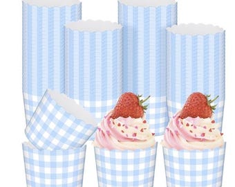 May include: A selection of blue and white gingham cupcake cases with a scalloped edge. Two cupcakes with pink icing, heart sprinkles, and strawberries are in the foreground. Stacks of empty cases are in the background.