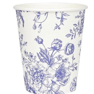 Op de afbeelding: Een witte papieren beker met een blauw bloemmotief. Het ontwerp bevat gedetailleerde illustraties van rozen, pioenrozen en andere bloemen en bladeren. De beker heeft een eenvoudig ontwerp met een gerolde rand.