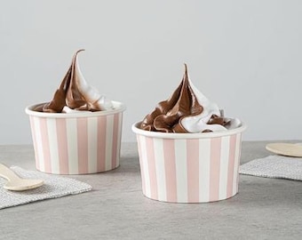 May include: Two ice cream desserts with chocolate and vanilla swirls in pink and white striped cups. A wooden spoon and a small napkin are on the left side of the image.