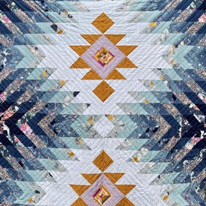 Könnte beinhalten: Eine Steppdecke mit einem geometrischen Muster in Blautönen, Weiß und Gold. Die Steppdecke hat eine große, zentrale Diamantform mit kleineren Diamanten darin. Die Steppdecke ist aus verschiedenen Stoffen gefertigt und hat eine handgenähte Optik.