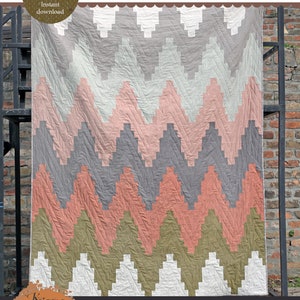 Pode incluir: Um padrão de colcha com um design chevron em tons de cinza, rosa, verde e branco. O padrão é chamado de "Chromaflick Chevron" e está disponível em três tamanhos: bebê (42" x 48"), manta (66" x 84") e cama (90" x 108").