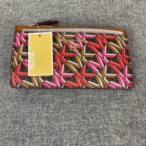 May include: A Michael Kors cardholder wallet with a geometric pattern in shades of pink, brown, and white. The wallet has a brown leather trim and the Michael Kors logo is visible. A price tag is attached.