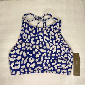 May include: A high-neck bikini top featuring a blue and white animal print pattern with crisscross straps at the back. The garment includes a brown paper tag attached to the side with the text J.CREW printed in white capital letters.