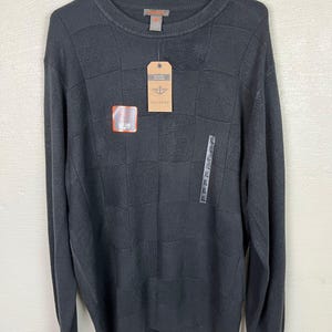 Könnte beinhalten: Ein schwarzer Langarm-Pullover mit einem strukturierten Muster. Der Pullover hat einen Rundhalsausschnitt und ist von Dockers.