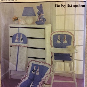 以下が含まれることがあります： ベビーハイチェア、おむつバッグ、ベビーキャリアの縫製パターンです。パターンは「デイジーキングダム」と呼ばれ、青と白の花柄にウサギが描かれています。