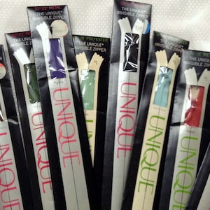 May include: A variety of zipper packages in black with silver accents. The zippers are in different colors, including red, green, blue, and purple. The packages have the text "The Unique Invisible Zipper" and "Unique" printed on them.