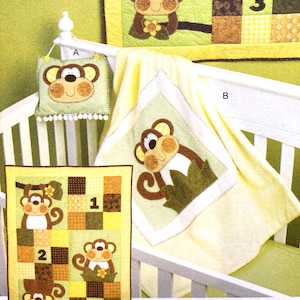May include: A crib set featuring a monkey theme. The set includes a pillow, a blanket, and a quilt. The quilt has three monkeys and the numbers 1, 2, and 3. The blanket is yellow with a monkey applique. The pillow is green with a monkey face.
