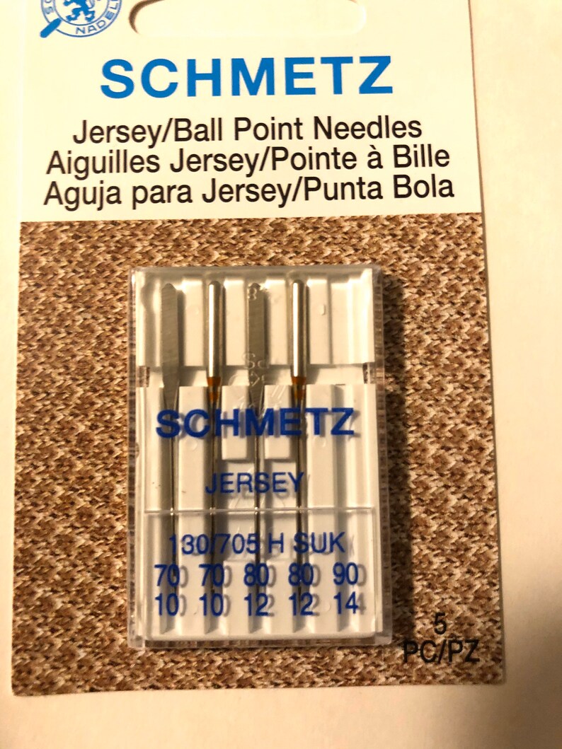 May include: A pack of five Schmetz Jersey/Ball Point needles for sewing. The needles are packaged in a clear plastic case with a white label that reads "Schmetz Jersey" and "130/705 H SUK". The label also lists the sizes of the needles: 70, 80, and 90. The pack is labeled "5 PC/PZ".